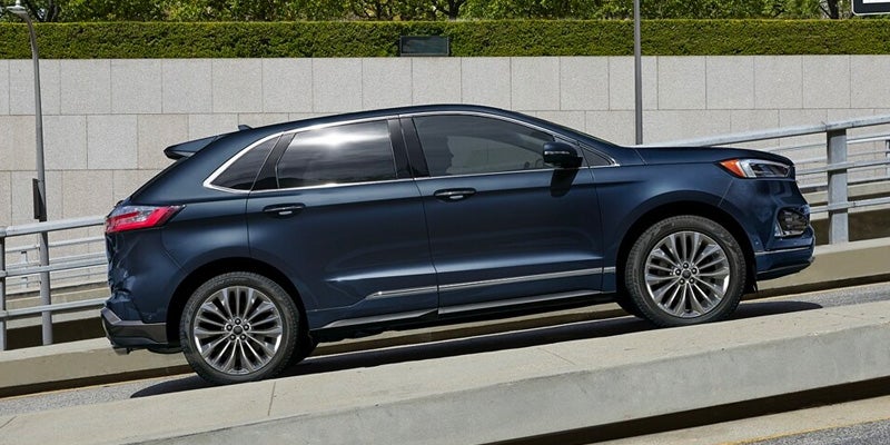 Dark blue SUV parked on an upward sloping concrete ramp, side profile view