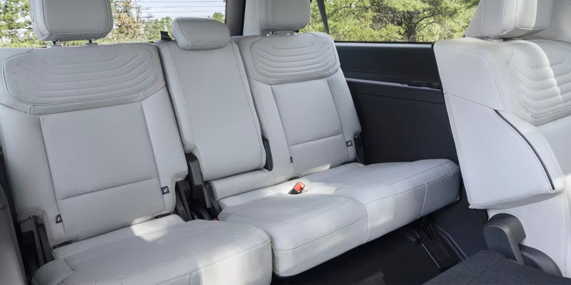 Light gray car seats with textured headrests, showing a two-person second row and a partially folded third-row seat.