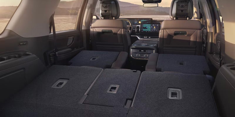 The spacious interior of an SUV with the third and second-row seats folded down, revealing a large cargo area.