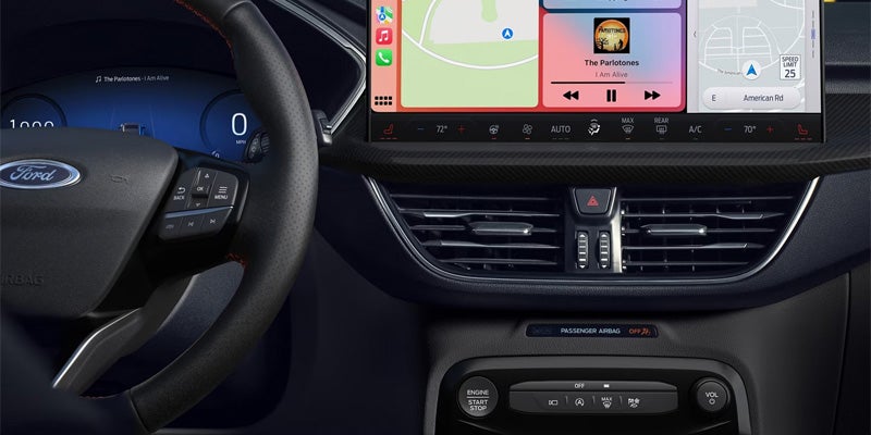 Car interior showing a Ford steering wheel, digital instrument cluster, and infotainment screen with Apple CarPlay.
