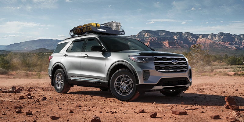 Ford Explorer with rooftop cargo carrier in an outdoor landscape.