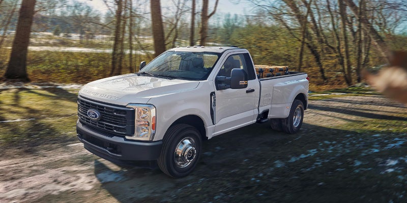 White Ford work truck driving on a rural road.