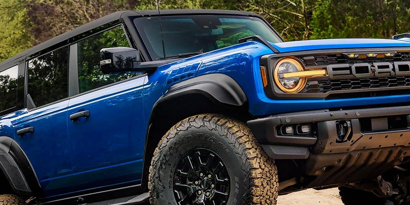 Blue Ford Bronco SUV with large off-road tires, amber headlights