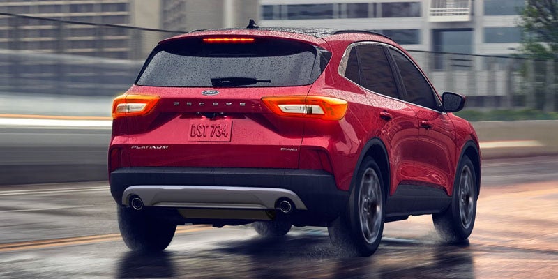 Red Ford Escape SUV seen from the rear, driving on a wet road