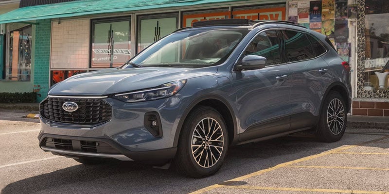 Gray Ford Escape SUV parked on asphalt in front of a storefront.