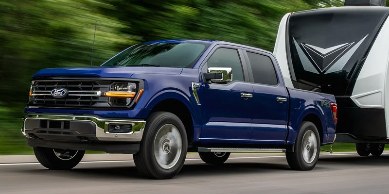 Blue Ford F-150 shown driving on a road.
