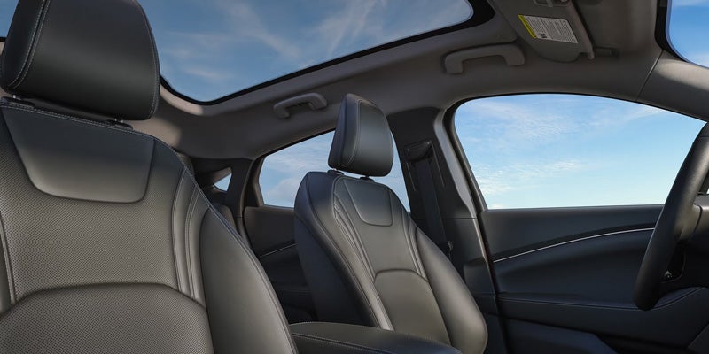 Vehicle interior featuring a panoramic glass roof and front seats.