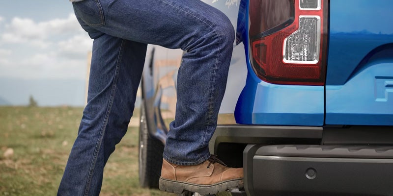 Person using a truck's integrated side step for easier bed access.