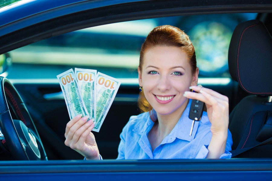 Person in a car holding cash and car keys.